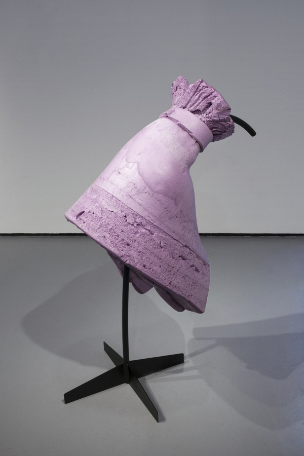 A closeup of a freestanding purple foam shape resembling a dress from the backside. The dress is supported by a tree-stand black metal frame.