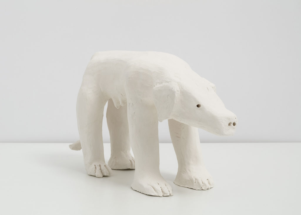 An off white ceramic sculpture of a labrador dog on all fours, but her front legs are human arms and hands.