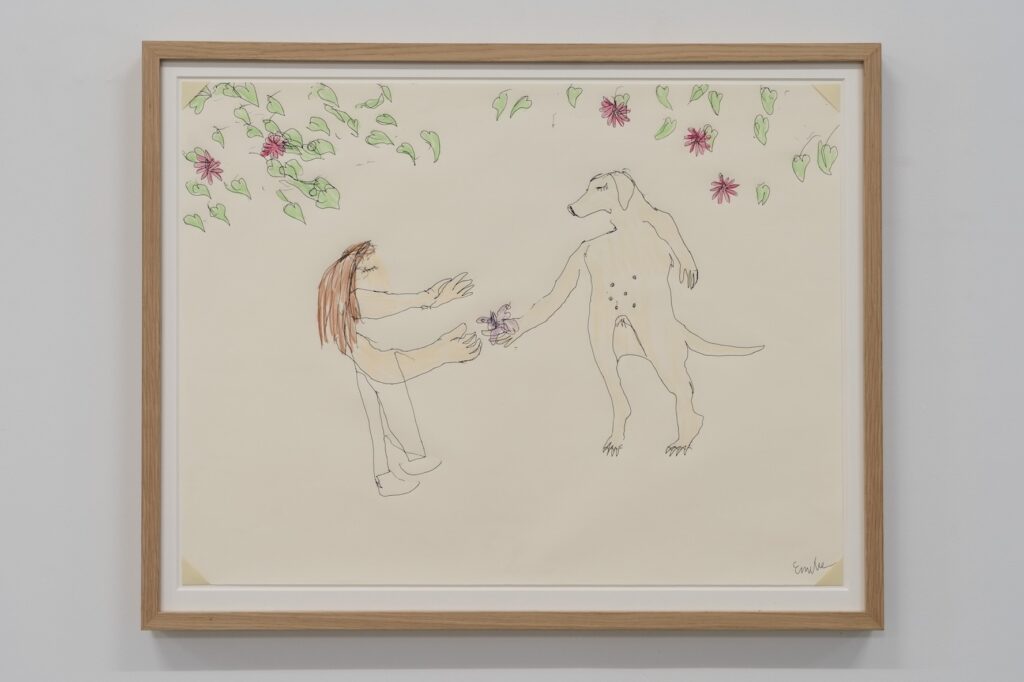 "The Gift" is a colored drawing on white paper slightly larger than a cookie tray. The drawing is framed in oak. Created with ballpoint pen and crayon, the artwork depicts a fantastical scene. Under a canopy of green leaves and purple flowers, which fill the top of the picture, Emilie stands in the foreground with outstretched arms, awaiting a gift from London. An anthropomorphized London, standing upright on her hind legs, extends a hand to offer a purple butterfly.