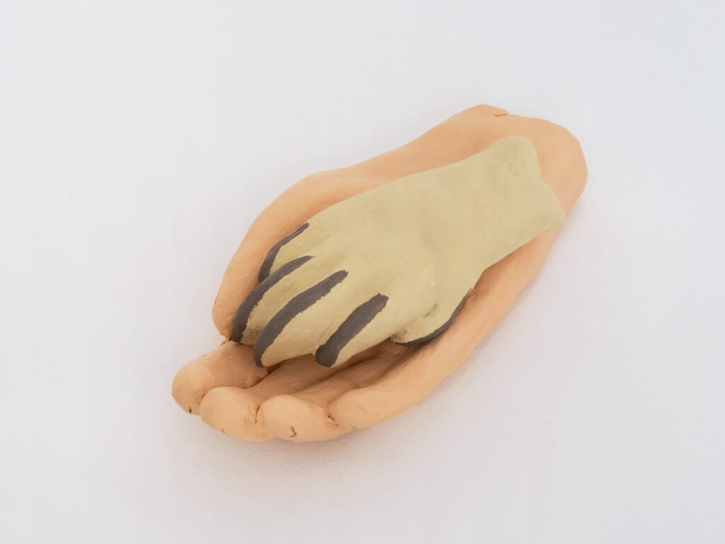 Detail view of "Paw and Hand" centered on the dog paw's thin nails and how gently the paw rests in the open palm of the human hand.